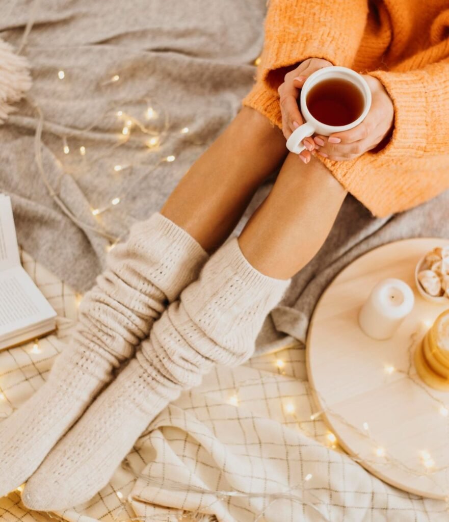 Femme en chaussettes de laine, une tasse de thé et un livre